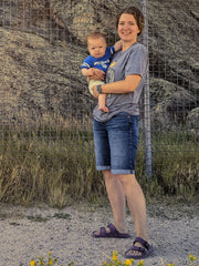 A woman holding a baby in front of a large rock formation