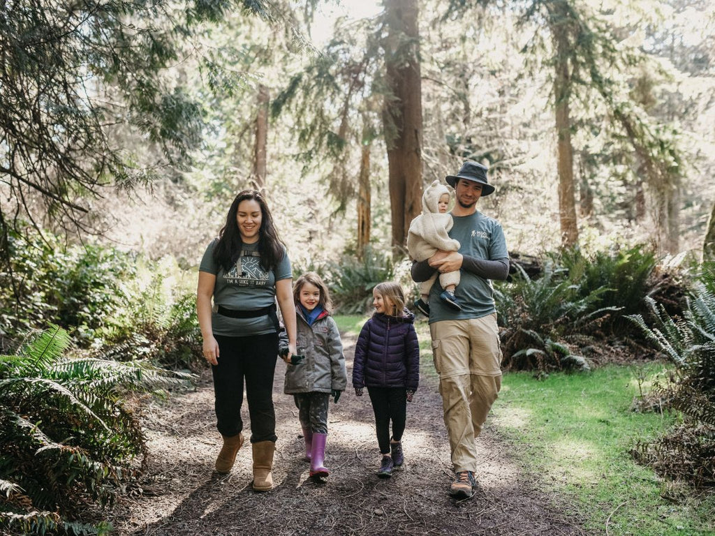 A family hiking in the forest with Hike it Baby shirts on