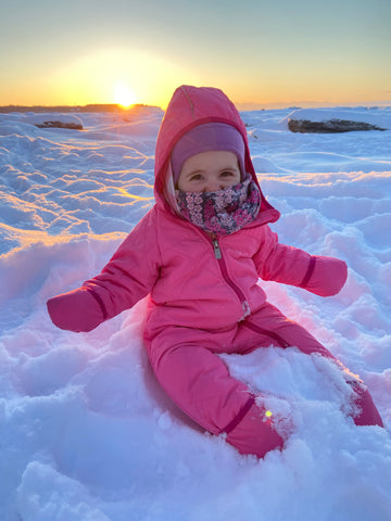 Baby playing in the snow at sunset