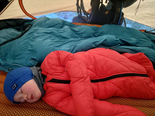 A young child sleeping in a tent wearing a Morrison Outdoors Big Mo Children's sleeping bag