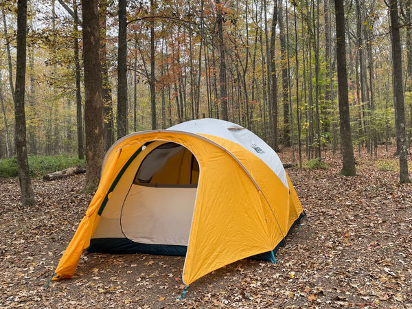 An REI Basecamp 6 tent in a forested area during fall