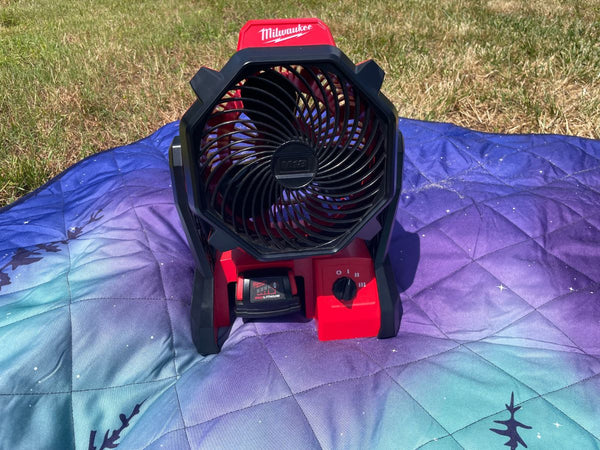 A Milwaukee jobsite fan on a blanket outdoors