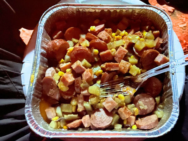 Camp foil packet containing sausage, potatoes, and veggies emptied into a bowl