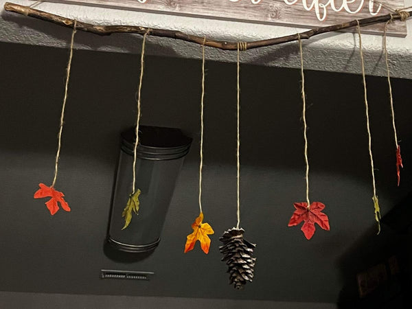 Fall leaves and a pinecone hanging from a stick