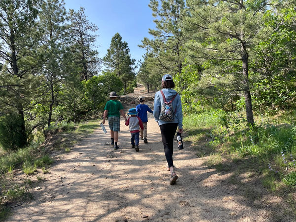 A family with four children hiking together along a dirt trail