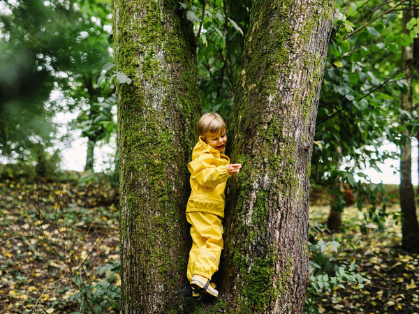 Young child in a Helly Hansen Rain suit climbing a tree