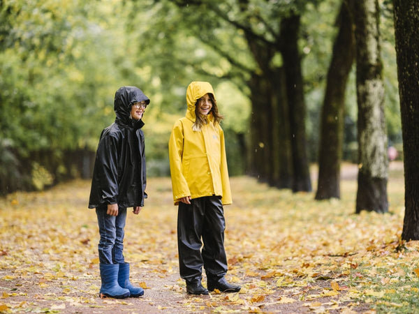 Kids wearing Helly Hansen rain gear while walking along a wooded path in the rain