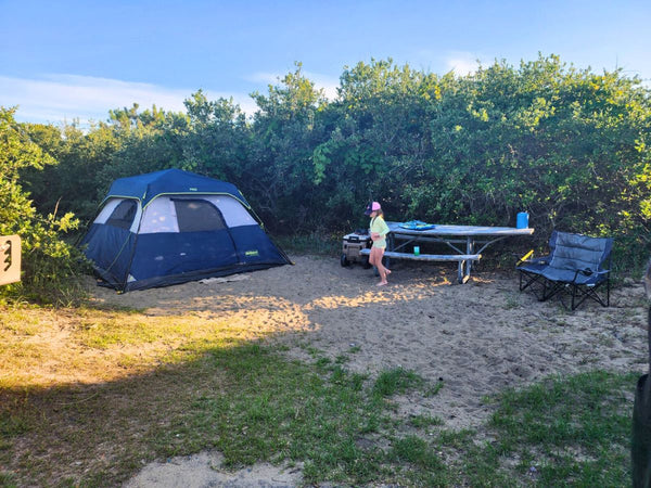 A young girl walking near a campsite on the beach in summer