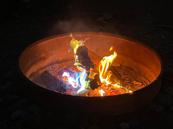 An outdoor fire pit burning logs with colorful flames