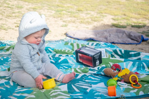 Baby playing on a blanket while camping.